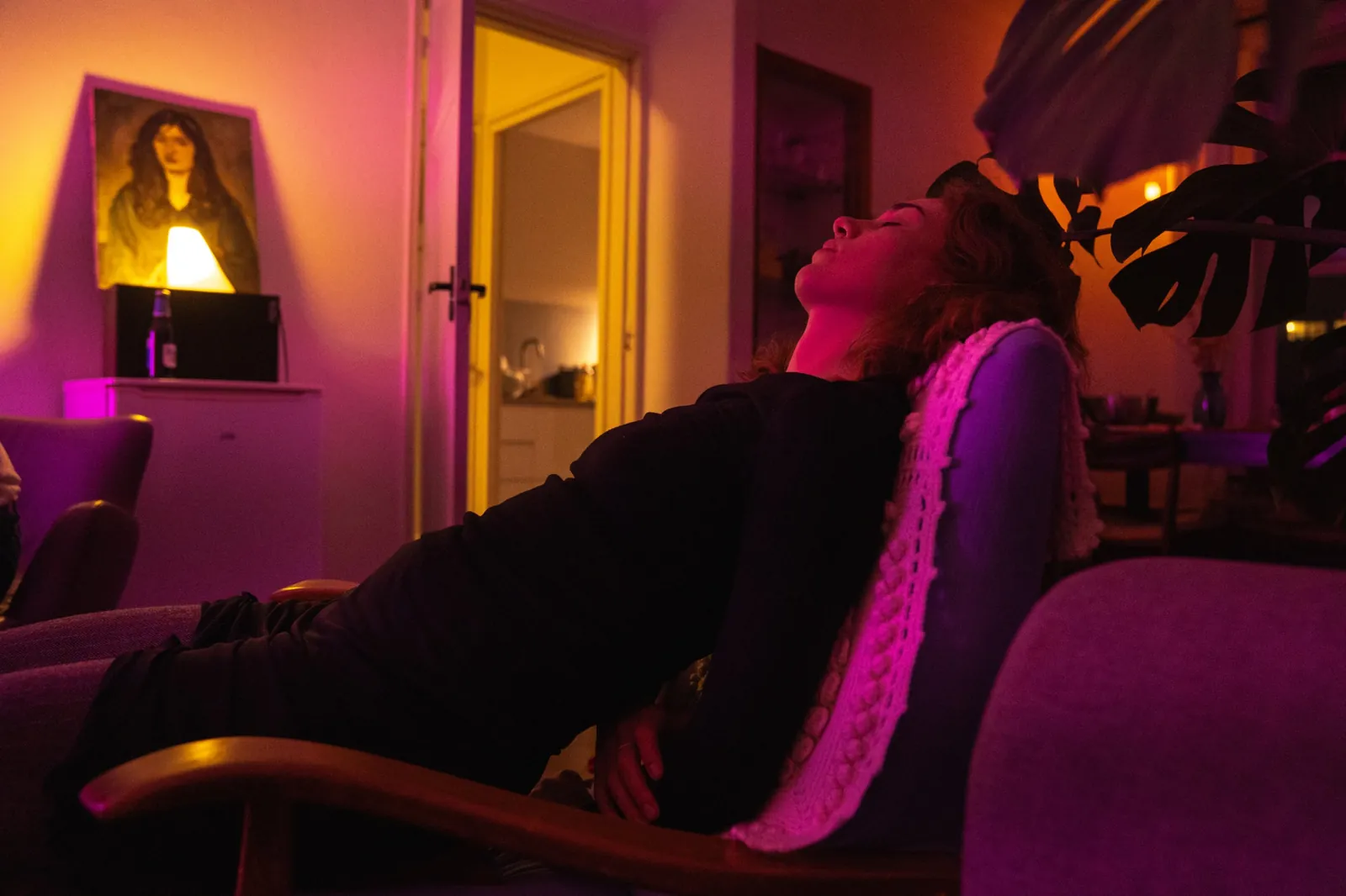 A woman leaning back in an armchair with her eyes closed while a song plays.